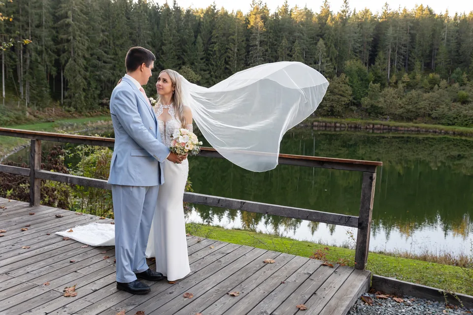 Hochzeitspaar auf dem Holzsteg am Haidensee, der Wind trägt den Brautschleier über das Wasser