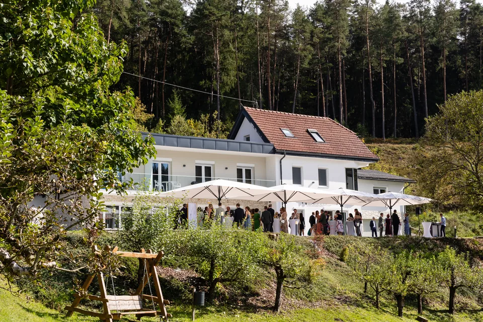 Das Haupthaus von Das Haidensee mit Sonnenschirmen auf der Terrasse, die Hochzeitsgäste bei der Agape