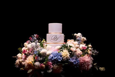 Hochzeitstorte mit Monogramm, umringt von Blüten