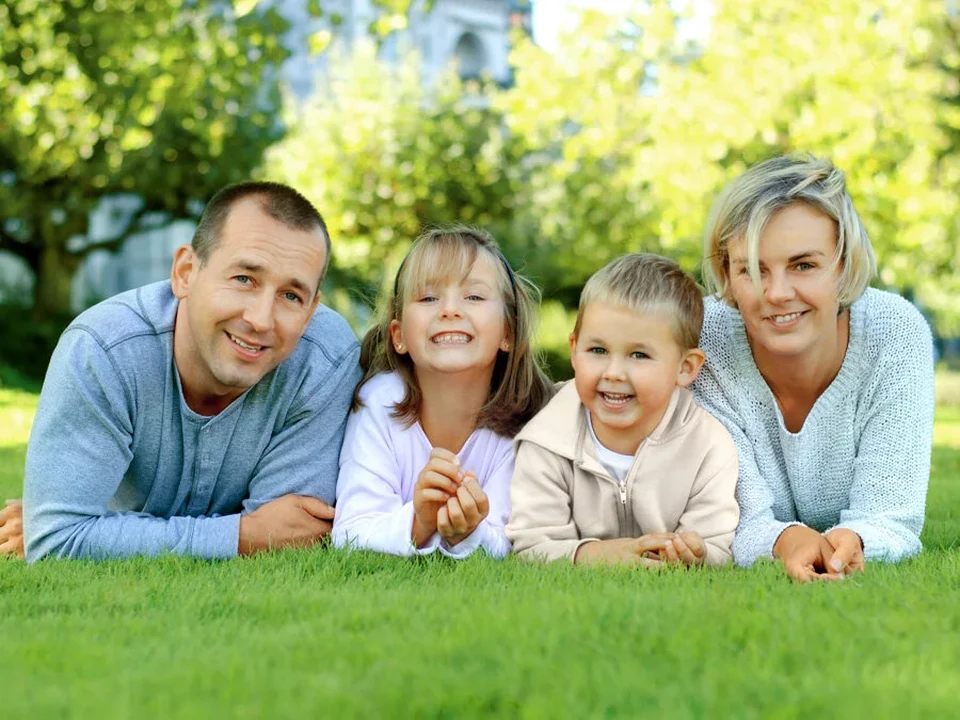 Family with two children lying on the grass, laughing