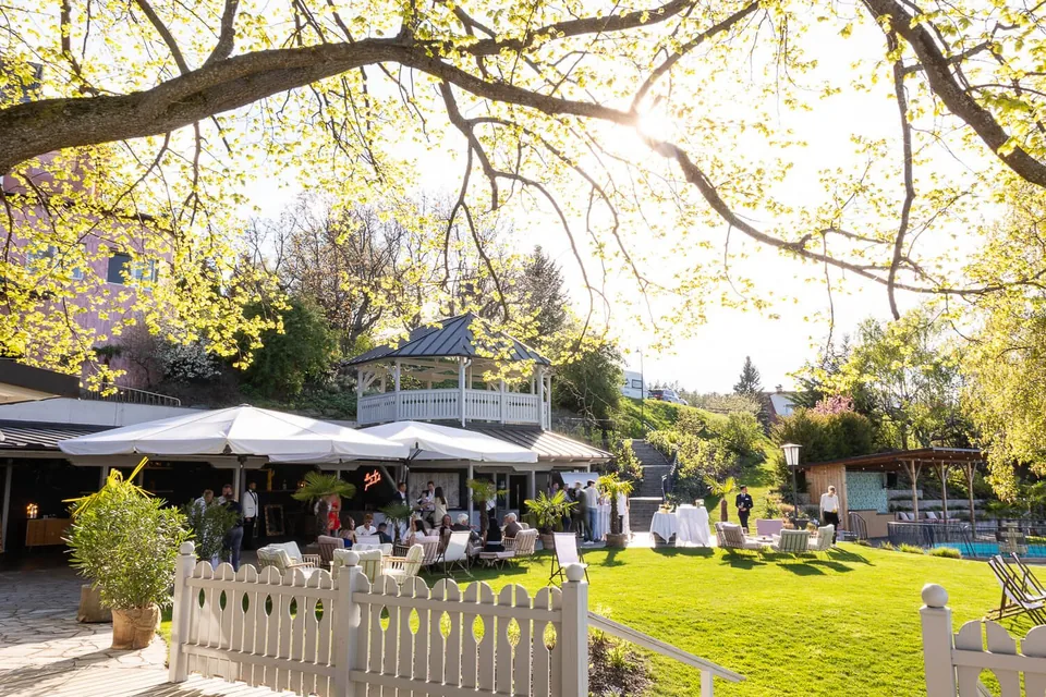 Garden terrace at the Fernblick with guests, parasols and pool in the evening sun