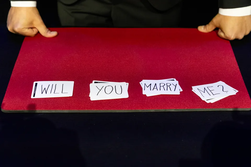 Spielkarten auf einem roten Tisch bilden die Frage Will you marry me, Magic World Vienna