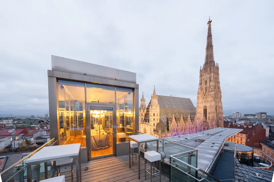 Beleuchteter Glaspavillon mit gedeckter Tafel neben dem Stephansdom zur blauen Stunde