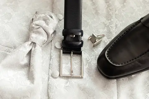 Gürtel, Schuhe und Manschettenknöpfe auf dem Bett der Hotelsuite