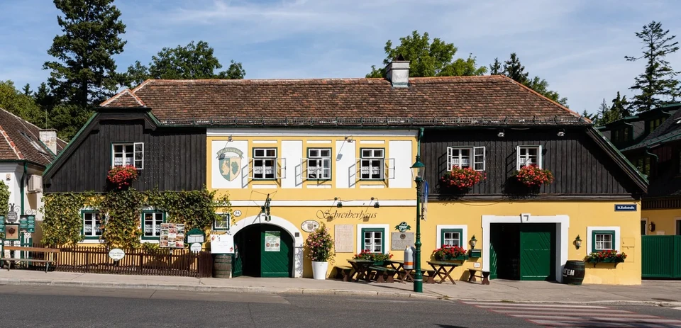 Exterior of the Schreiberhaus with its yellow facade, a traditional wine tavern in Neustift am Walde