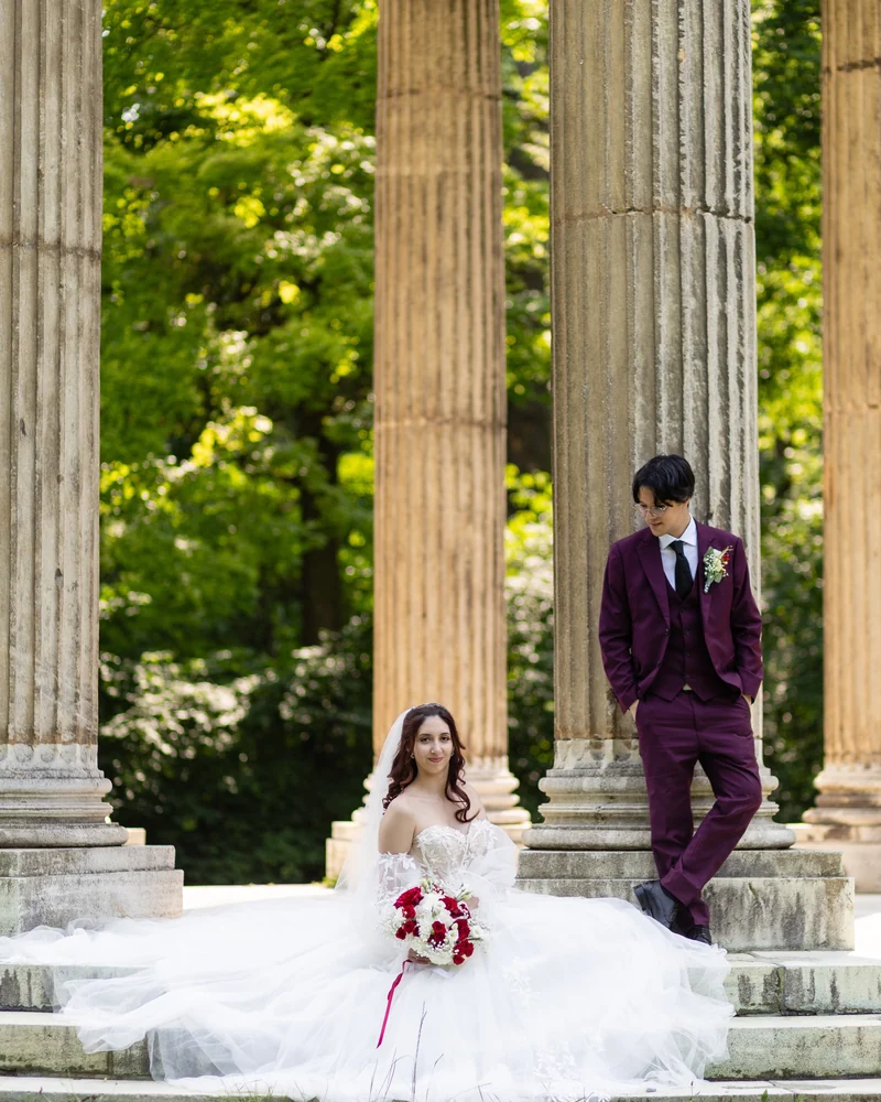 Hochzeitspaar an klassischen Säulen im Schlosspark Laxenburg im Sommer