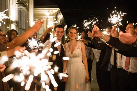 Hochzeitspaar beim Sparkler-Auszug, Gäste bilden ein Spalier mit Wunderkerzen