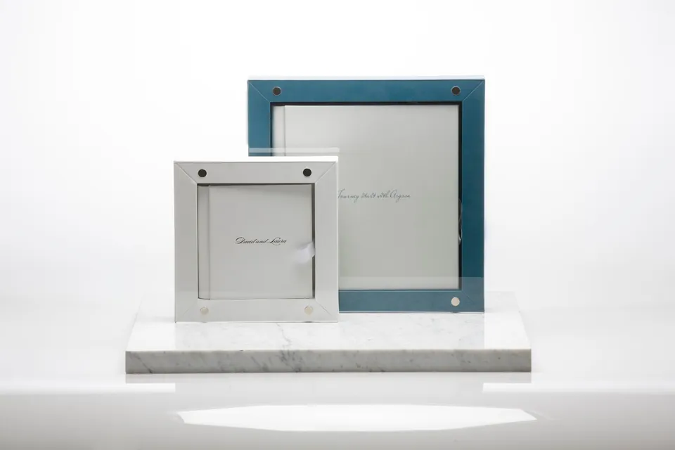 Zwei Rome Hochzeitsalben in Weiß und Blau hinter Acrylglas auf einem Marmorsockel
