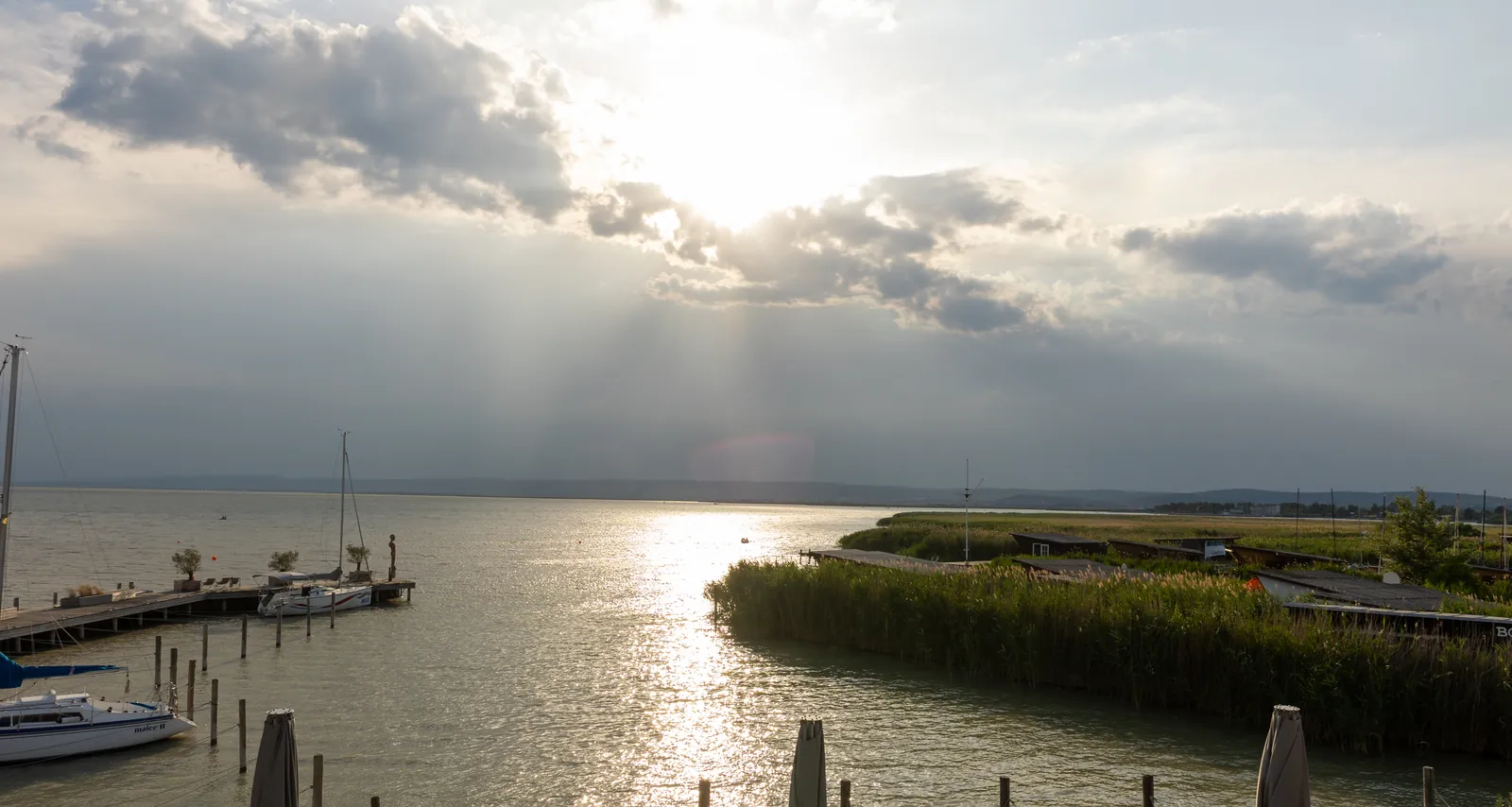 Abendsonne über dem Neusiedler See in Weiden, mit Bootssteg und Schilfgürtel