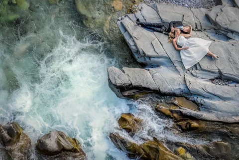 Aerial view of a wedding couple by a wild river