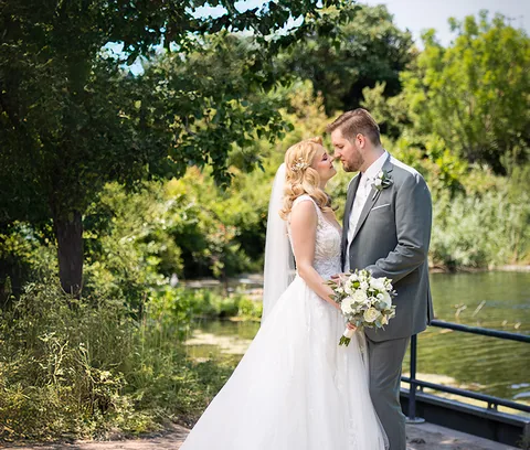Intimate moment of a wedding couple by a pond surrounded by greenery
