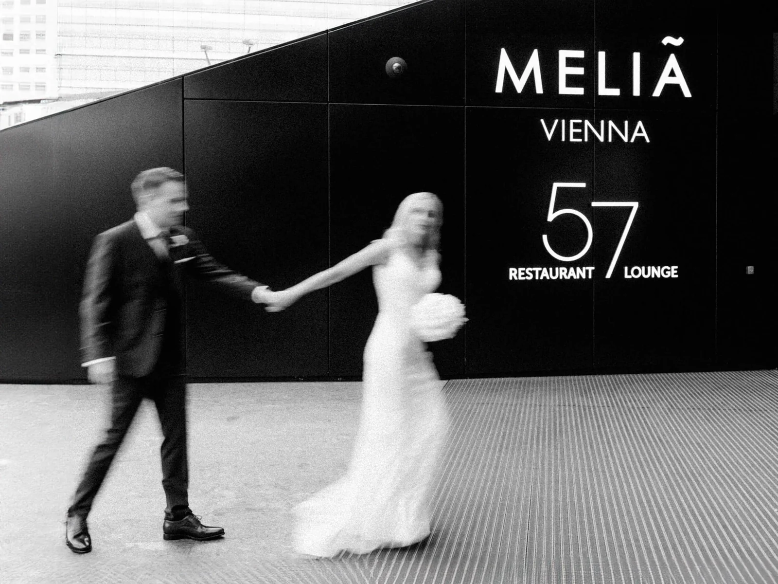 Hochzeitspaar in Bewegungsunschärfe an einer Fassade in Wien, in Schwarzweiß