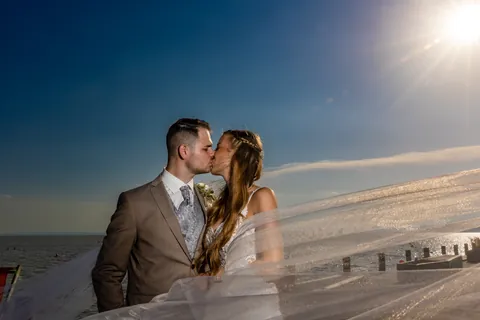 Hochzeitspaar küsst sich am Steg des Neusiedler Sees im Gegenlicht