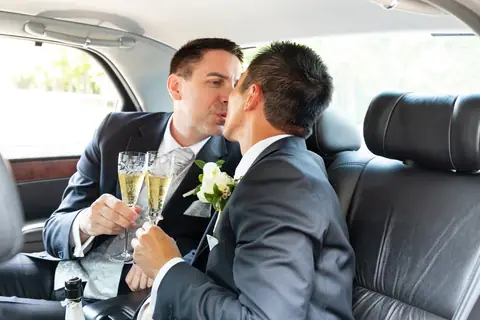 Die Bräutigame küssen sich mit Champagner in der Limousine