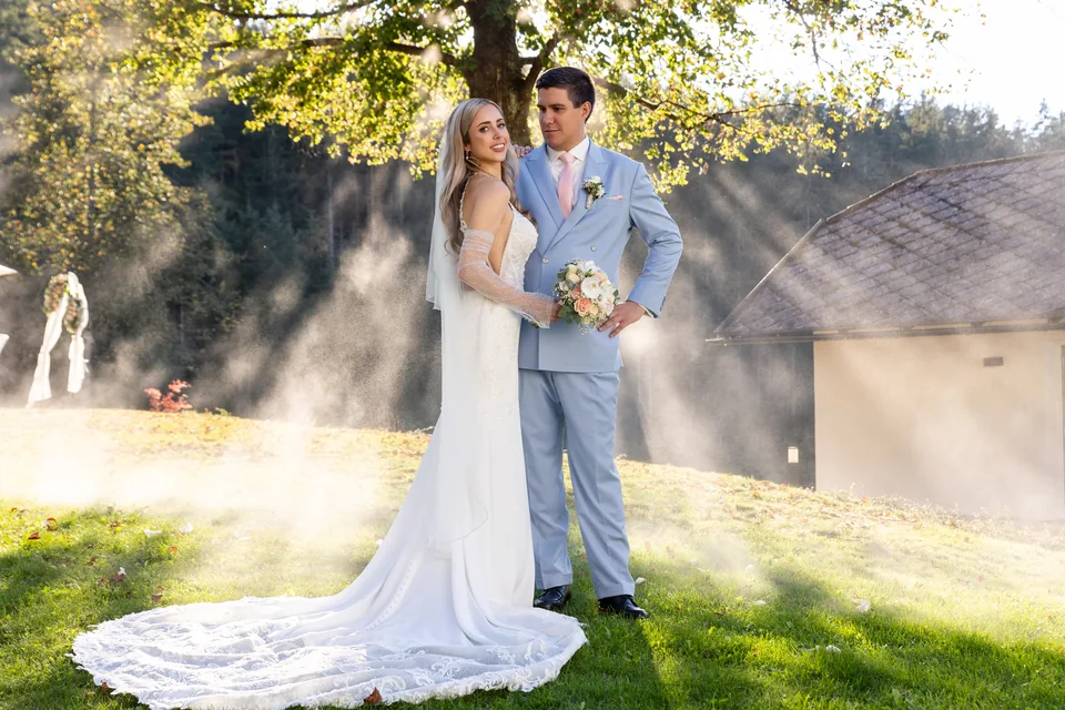 Hochzeitspaar unter dem großen Baum, Sonnenstrahlen fallen durch Nebel auf die Wiese