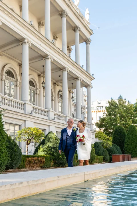 Hochzeitspaar spaziert vor dem Palais Coburg in Wien und blickt einander an
