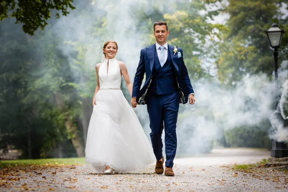Hochzeitspaar geht Hand in Hand durch einen herbstlichen Park