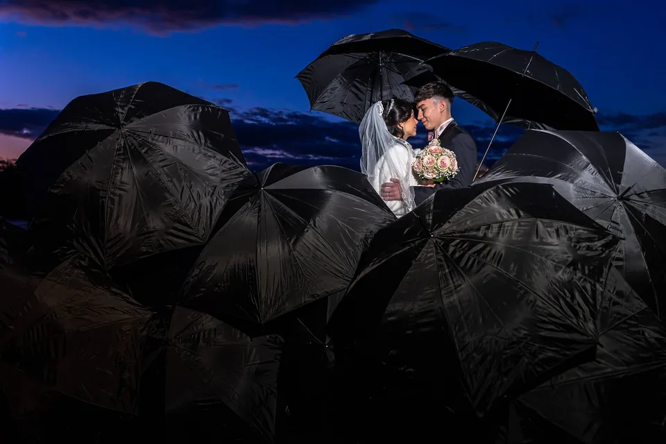 Wedding couple at night under black umbrellas, atmospheric portrait
