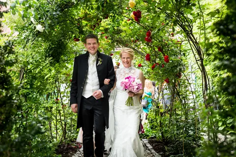 Hochzeitspaar unter einem Rosenbogen in Rust