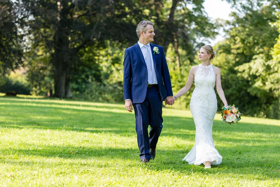 Hochzeitspaar geht Hand in Hand über die Wiese im Schlosspark Hernstein