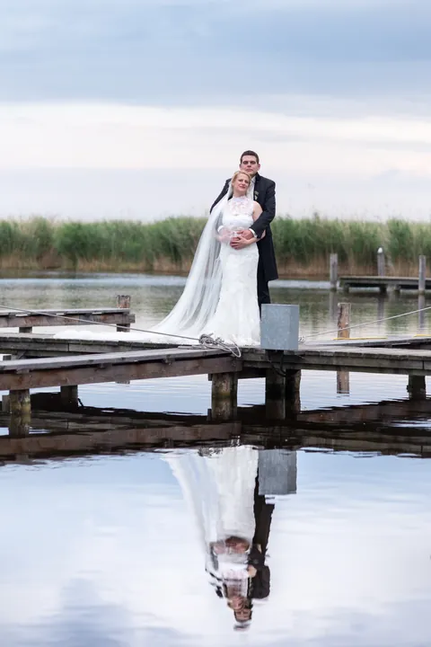 Hochzeitspaar am Steg im Schilf, gespiegelt im Wasser des Neusiedler Sees bei Rust