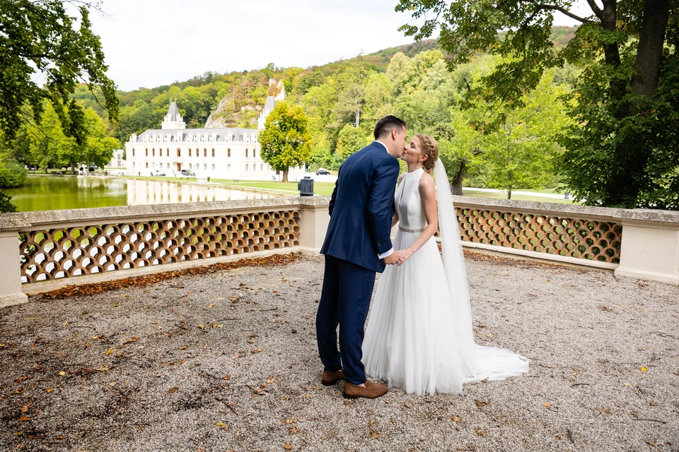 Hochzeitspaar auf der Terrasse, dahinter spiegelt sich Schloss Hernstein im Teich