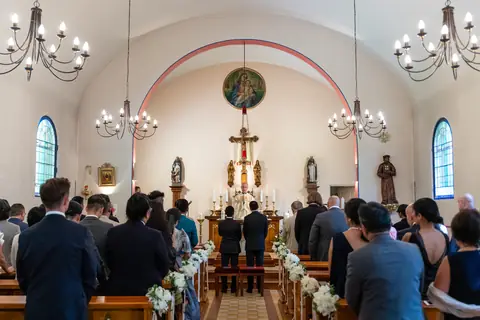 Die Gäste sitzen in der Kapelle Maria Grün, vorne stehen die Bräutigame