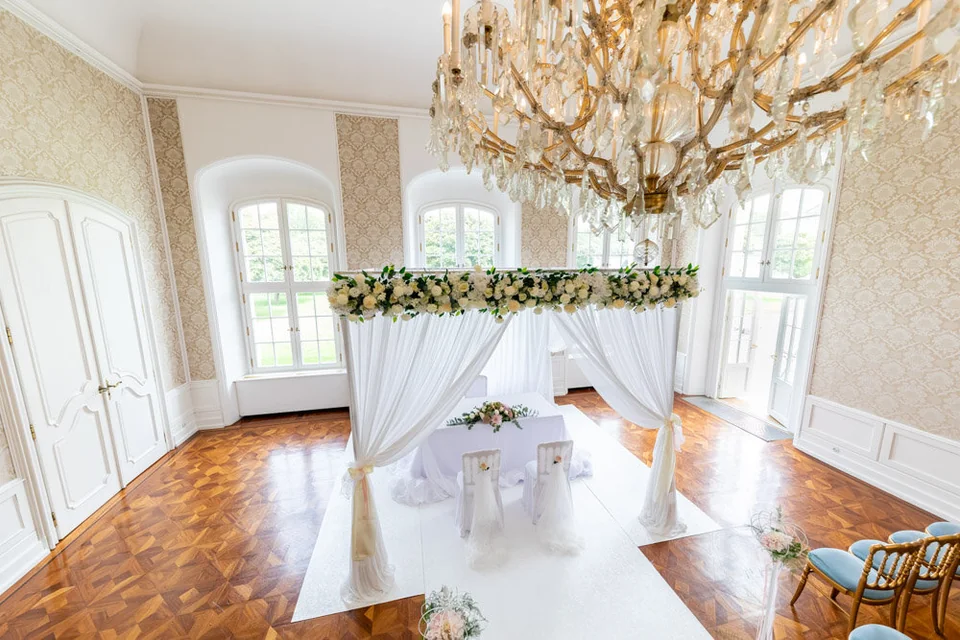 Für die Trauung hergerichteter Prunksaal in Schloss Laxenburg mit Luster und Blumenbogen