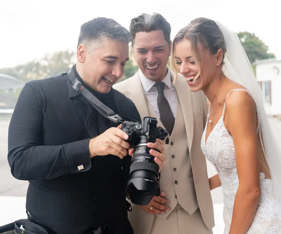 Michael Kobler zeigt einem Hochzeitspaar die ersten Bilder auf der Kamera, alle drei lachen