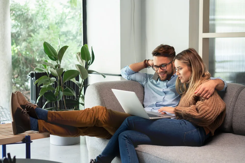 Couple in love planning their wedding with a laptop on the sofa