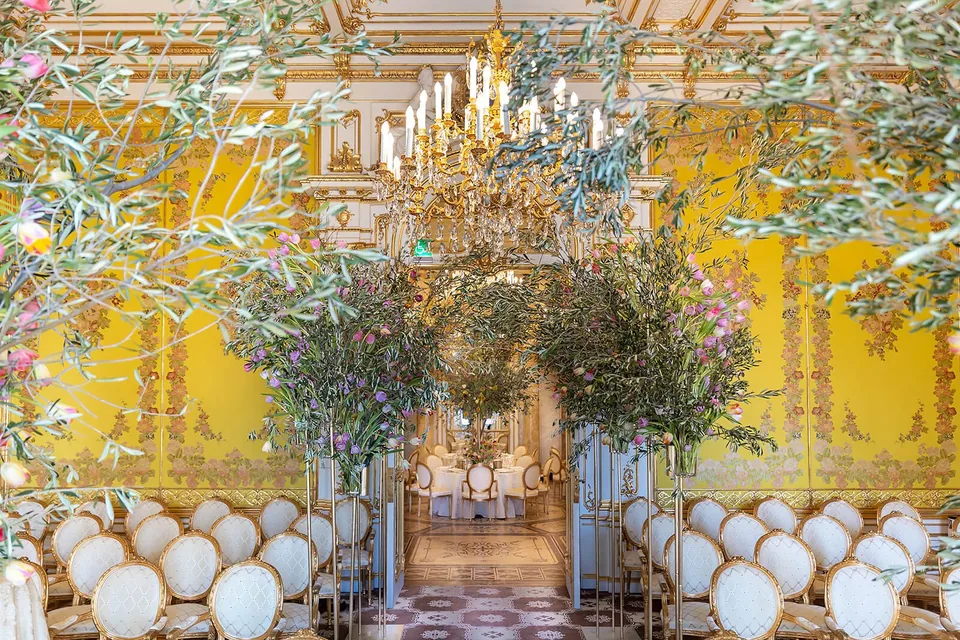 Grand hall at Palais Coburg with yellow silk walls, chandeliers and festive seating