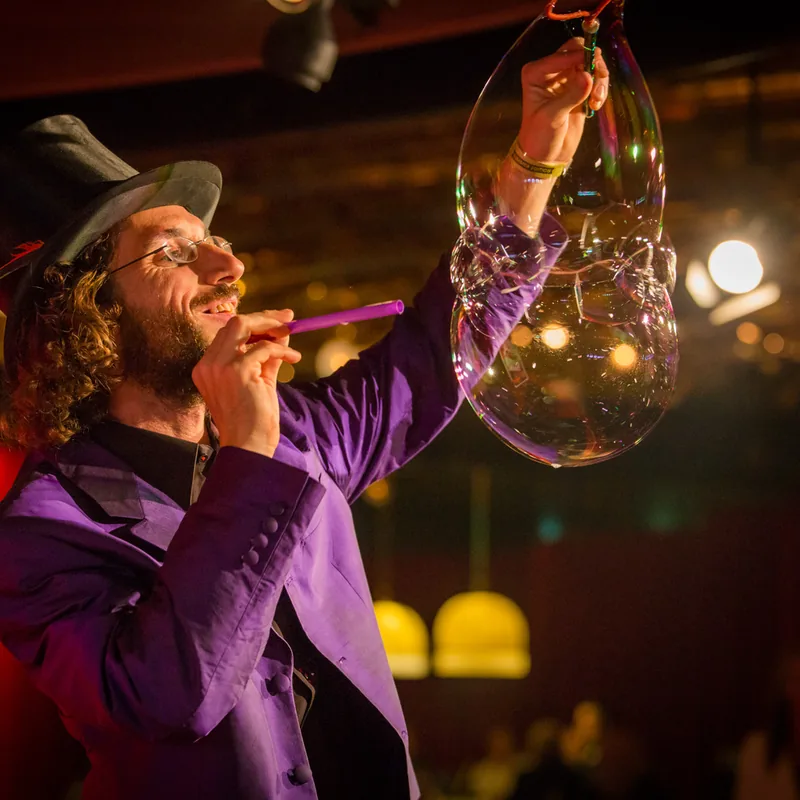 Aramis Gehberger of Dr. Bubbles shaping a large soap bubble during a stage show