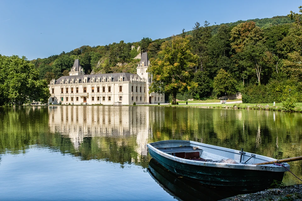 Schloss Hernstein spiegelt sich im Teich, am Ufer liegt das Ruderboot bereit
