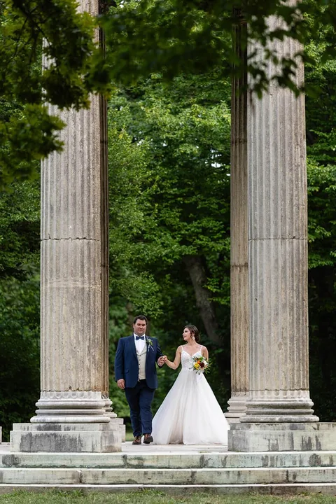 Hochzeitspaar zwischen historischen Säulen im Schlosspark Laxenburg
