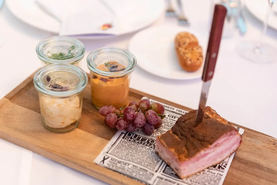 Three-way tasting with speck and spreads on a wooden board at Schreiberhaus