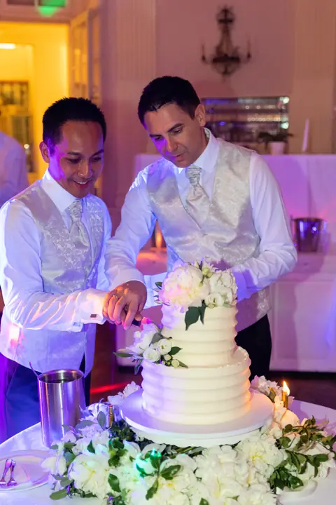 Die Bräutigame schneiden gemeinsam die Hochzeitstorte an