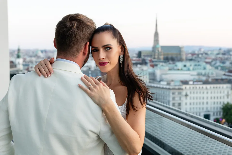 Engaged couple on a rooftop terrace with a view of St. Stephen's Cathedral in Vienna