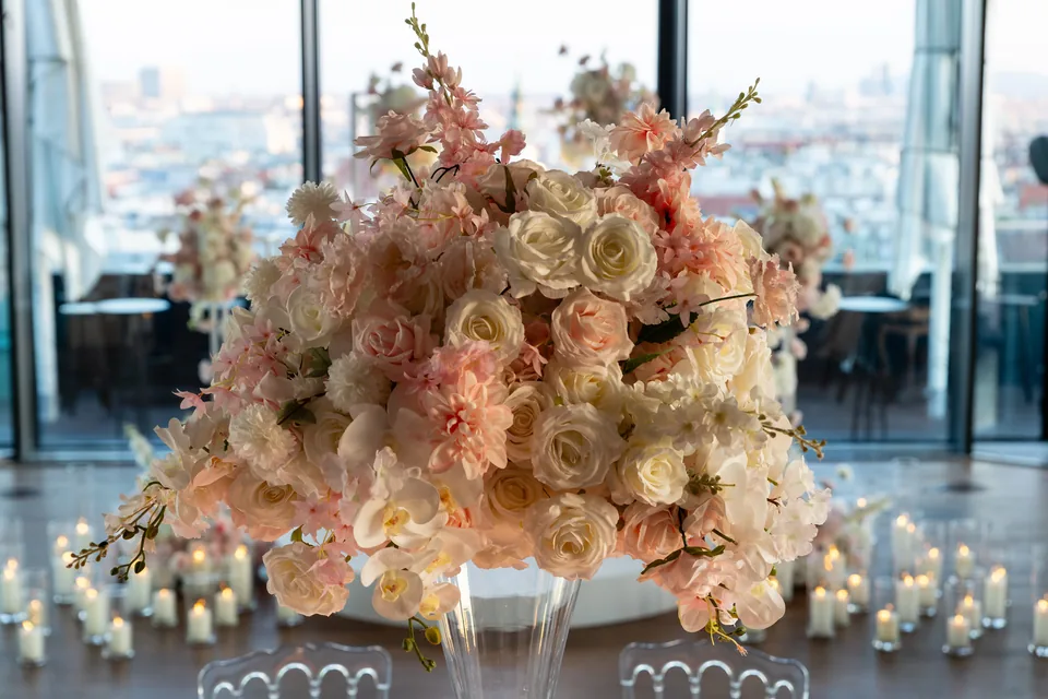 Flower arrangement with candles in front of the window front at Juwel Vienna, the city behind