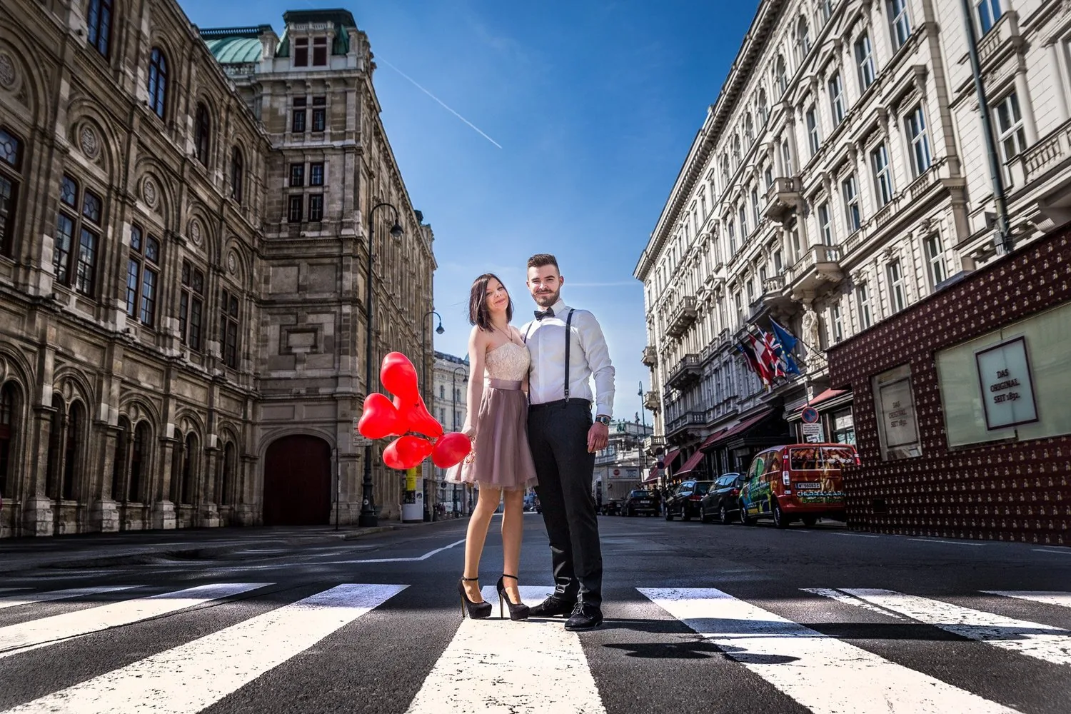 Paar mit roten Herzluftballons vor der Wiener Staatsoper