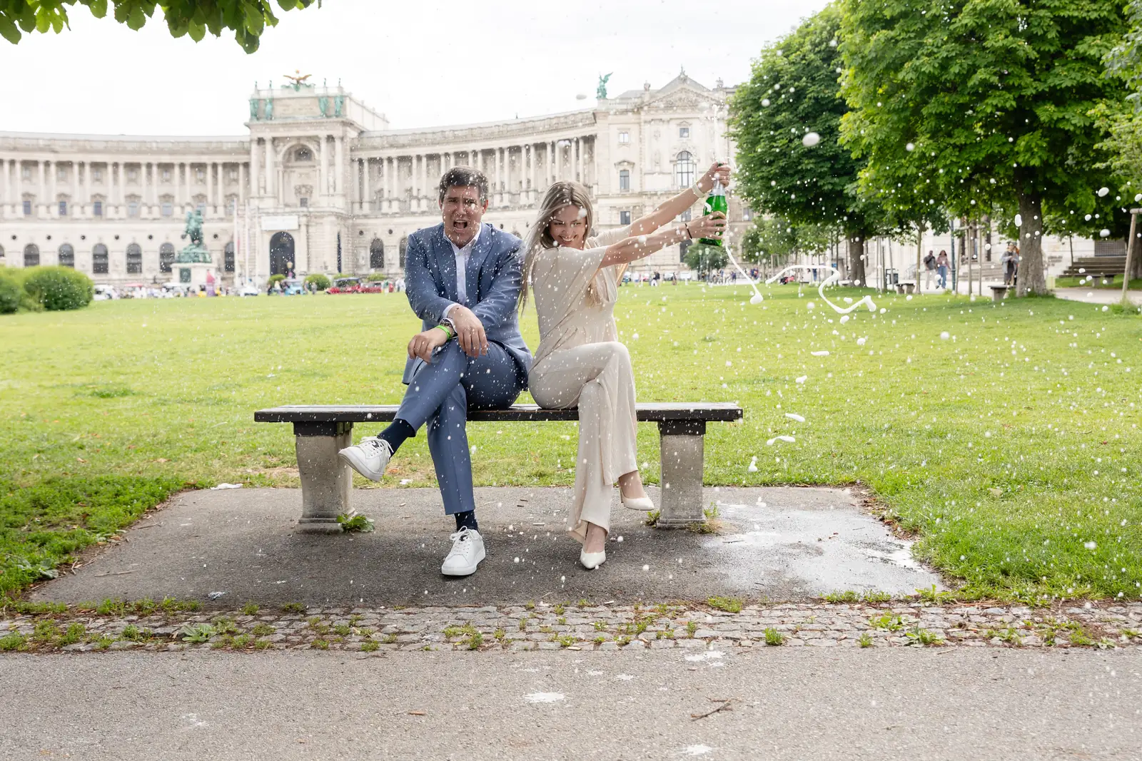 Newly engaged couple popping champagne in front of Vienna's Hofburg