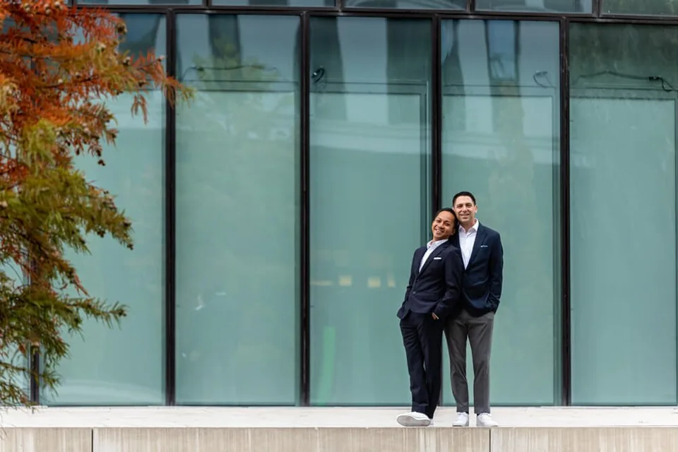Newly engaged same-sex couple in front of modern architecture in Vienna