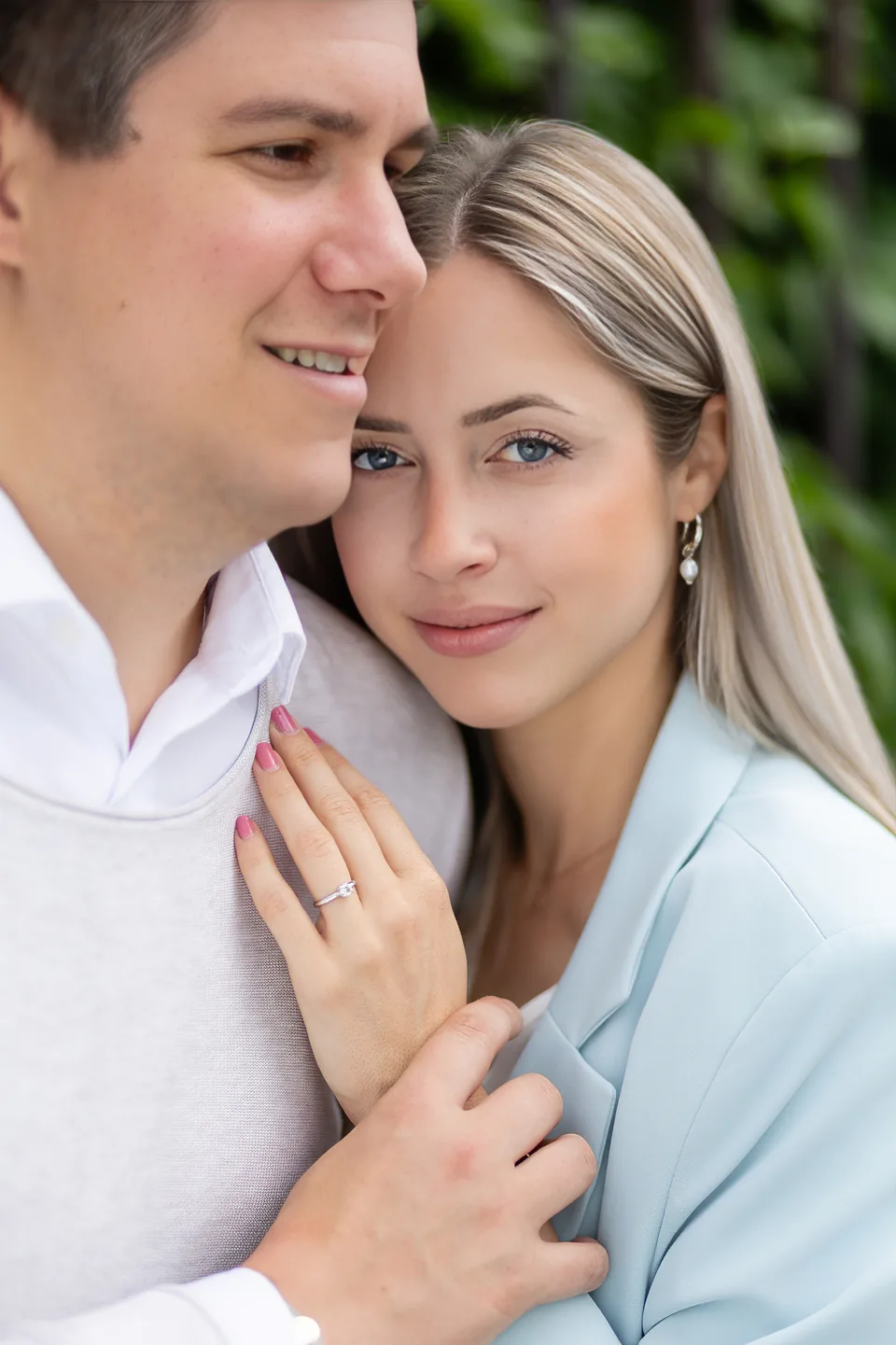Newly engaged woman nestling against her partner, her ring hand resting on his chest
