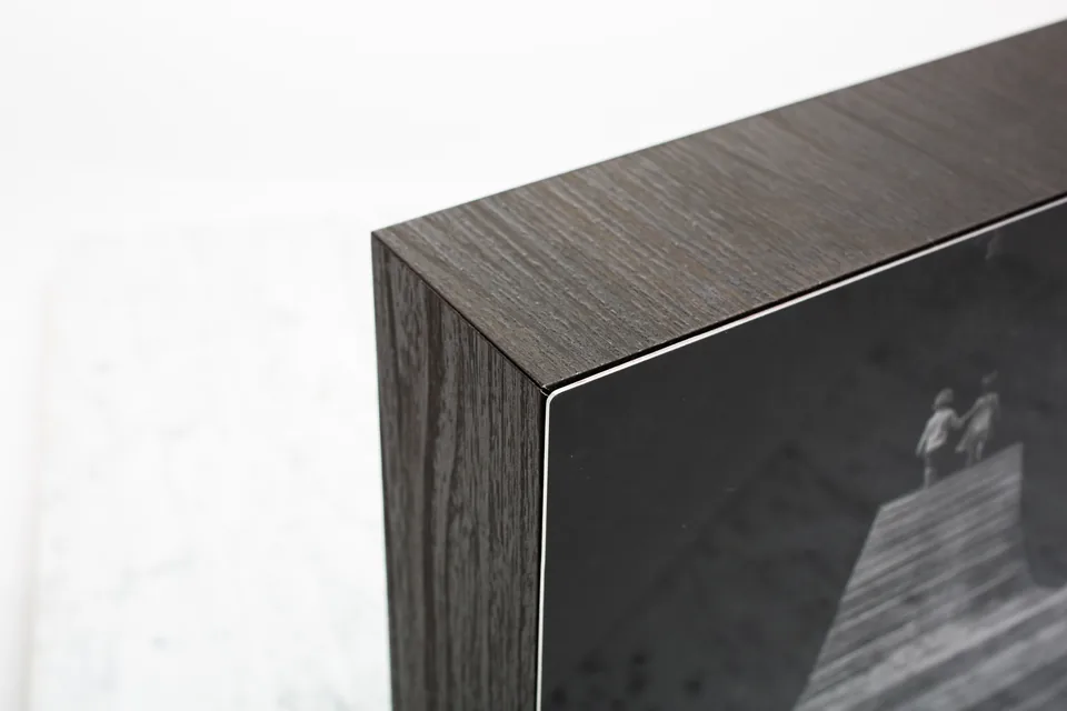 Kante eines Metall-Prints mit metallischem Glanz und Holzpaneel