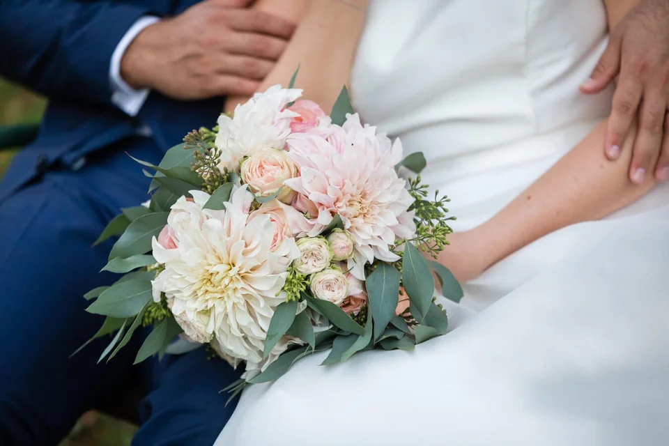 Brautstrauß mit rosa Dahlien vor dem Brautkleid