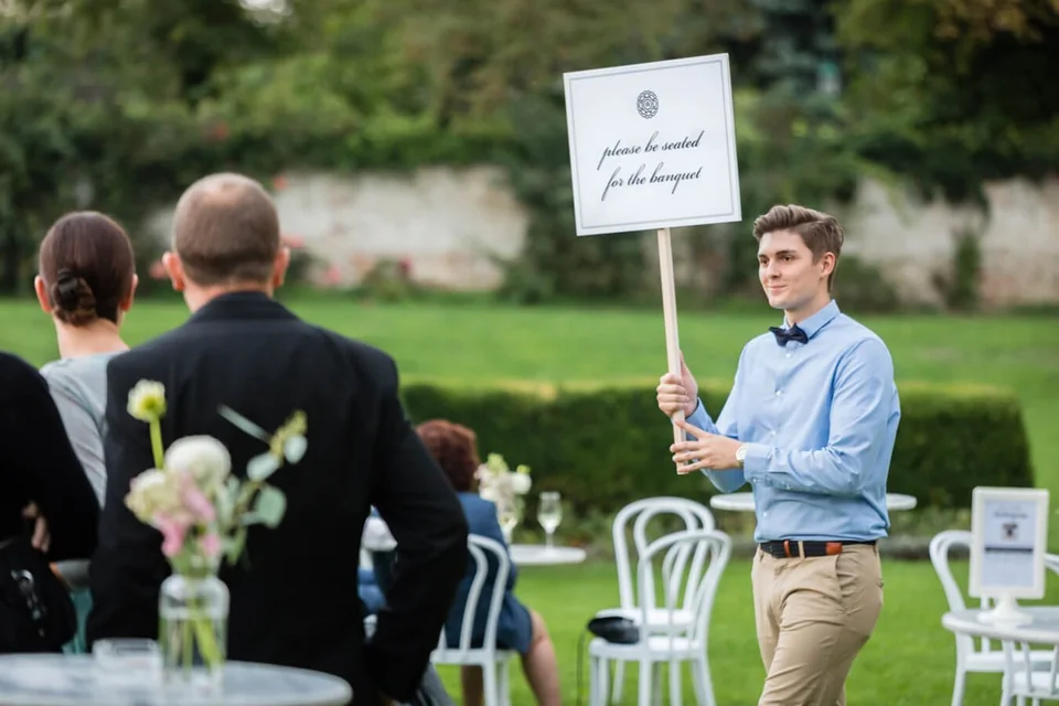 Wedding Steward mit Hinweisschild bei der Gartentrauung im Schlosspark